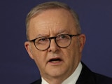 A politician stands in front of the Australian flag.
