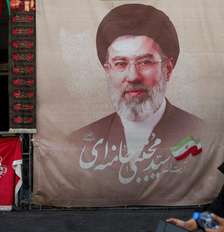 Uma mulher caminha ao lado de um cartaz com a imagem do líder supremo do Irã, Mojtaba Khamenei, em uma rua de Teerã, Irã, em 13 de agosto de 2026. Foto: via REUTERS - Majid Asgaripour / RFI