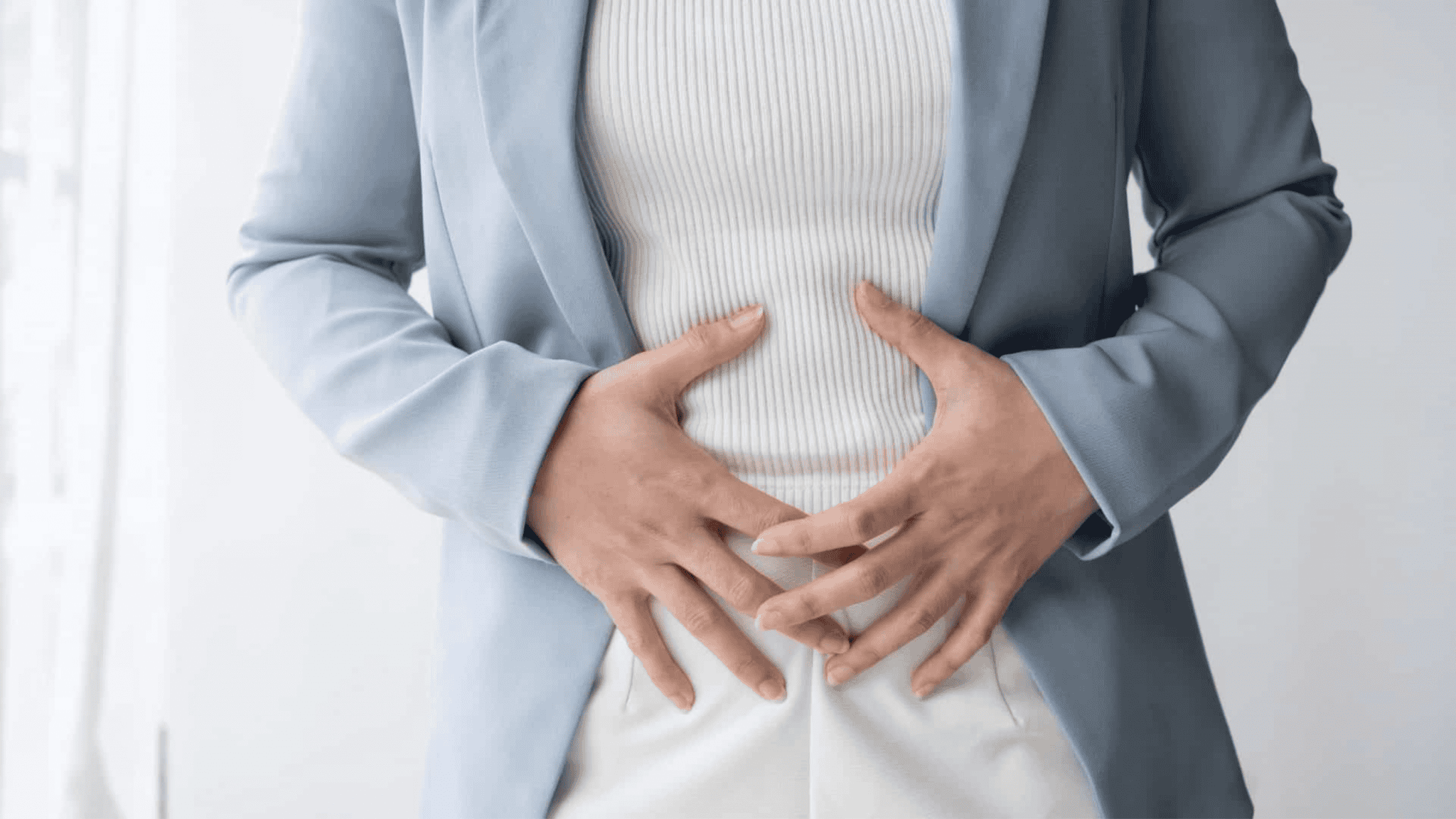 Mulher com as mãos na barriga devido à dor