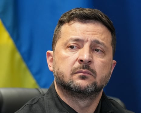 Volodymyr Zelenskyy looks on, with the Ukrainian flag's colours in background