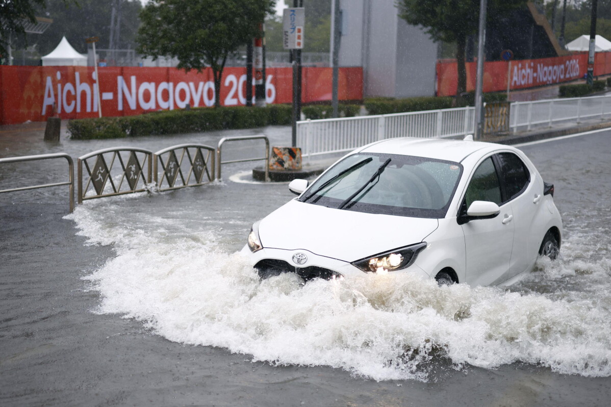 A car drives along a flooded road following heavy rain with a banner for the Aichi-Nagoya Asian Games in the background in Nagoya, central Japan, on Tuesday, Sept. 8, 2026. (Natsumi Yasumoto/Kyodo News via AP)