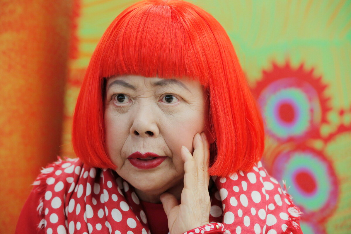 Japanese avant-garde artist Yayoi Kusama, wearing a bright red wig and a Louis Vuitton polka dot scarf, speaks during an interview at her studio in Tokyo, on Aug. 1, 2012. (AP Photo/Itsuo Inouye, File)