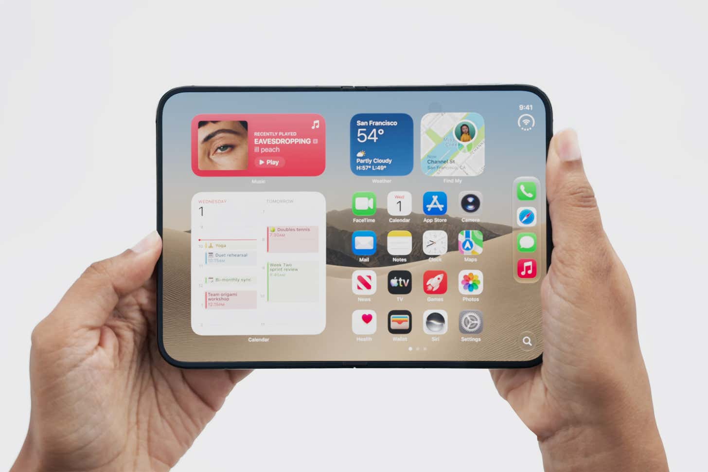 An individual holds an Apple iPhone Duo with both hands against a plain white background. The screen displays a home screen layout featuring various colorful app icons and calendar widgets.