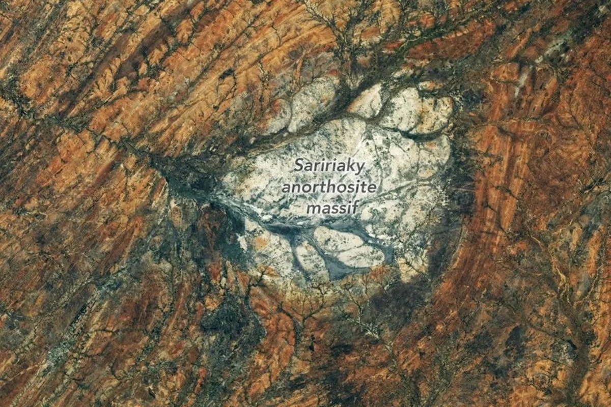 Foto colorida tirada de satélite que mostra aréa rochosa com várias montanhas. No centro uma mancha branca - Metrópoles.
